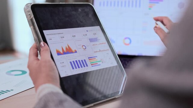 businesswoman hands using digital tablet and analyzing sales performance data and financial charts with a laptop computer in a modern office.