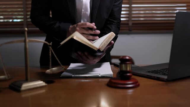 lawyer or attorney working in a law office and reviewing legal documents at The wooden desk features a gavel scales of justice and a notebook creating a classic and formal legal atmosphere.
