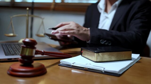 lawyer or attorney working in a law office and reviewing legal documents at The wooden desk features a gavel scales of justice and a notebook creating a classic and formal legal atmosphere.