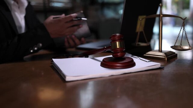 lawyer or attorney working in a law office and reviewing legal documents at The wooden desk features a gavel scales of justice and a notebook creating a classic and formal legal atmosphere.