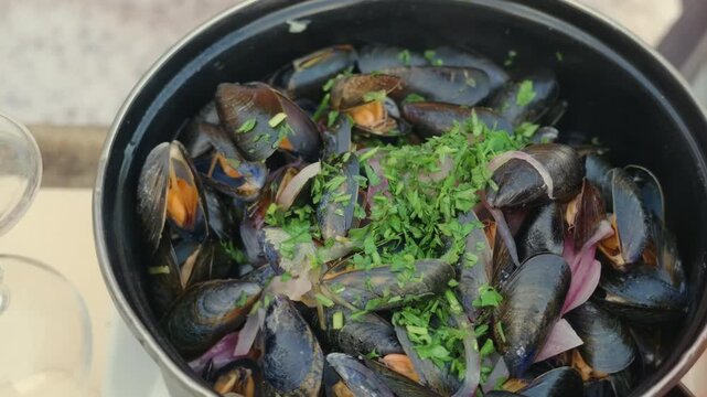 Close-up of a pot of mussels topped with parsley and red onion, Cote d'Azur, France