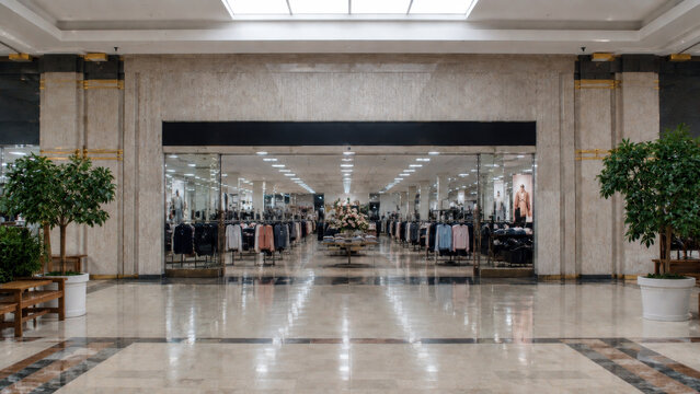 Large clothing store inside a modern shopping mall with open entrance, bright interior and rows of fashion displays
