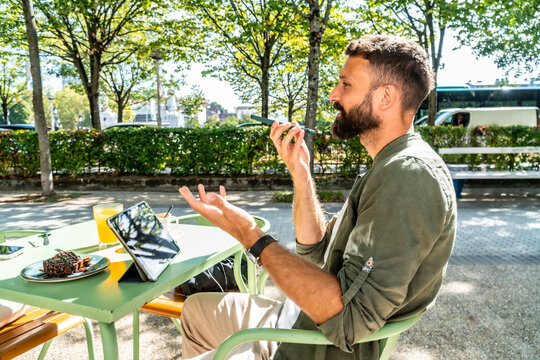 Man working remotely talking on smartphone at cafe