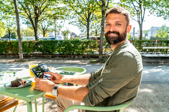 Man smiling working on tablet at outdoor cafe