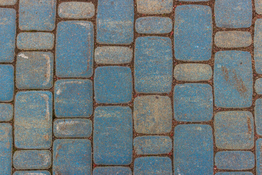 Close-up view of blue and gray cobblestone pavers arranged vertically, featuring a rough, weathered texture and wide joints between the blocks.