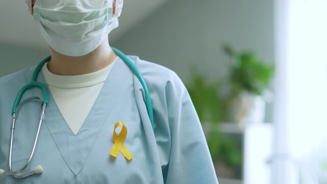 Medical staff holds yellow awareness ribbon symbol in hospital ward. Caregiver displays token of hope with solemn gesture. This closeup captures tender support for children battling cancer