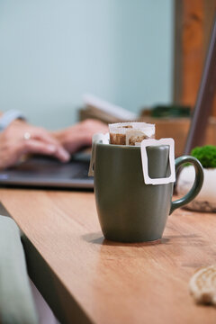 drip coffee in the cup on counter in the morning, laptop in the background