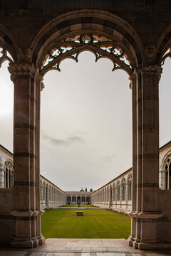 Historic Gothic cloister with elegant stone arches, carved columns, and a peaceful green courtyard illuminated by soft natural light