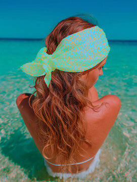 The scene shows a serene woman seated by the sea. It is ideal for fashion editorials, beauty campaigns, and social media.