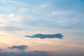 Obraz premium Calm evening sky with thin clouds in pastel blue and peach hues