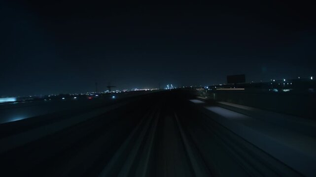Front POV glides along an elevated railway track passing a speeding oncoming train at night before moving toward distant city lights