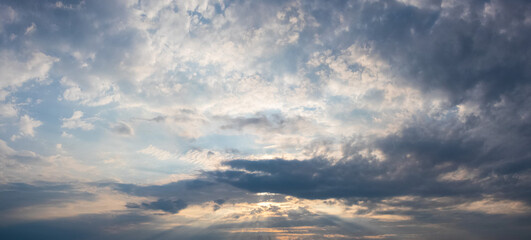 Obraz premium Dramatic sky with clouds and sun rays breaking through them at dusk