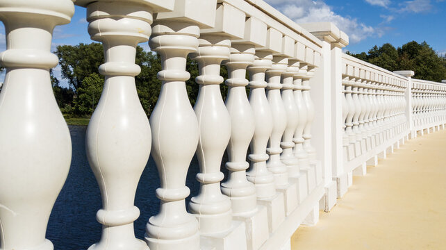 White Stone Balusters in Bridge Railing over River under Blue Sky. Classic Architectural Design Concept