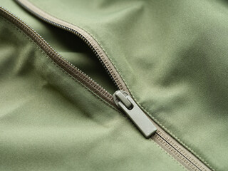 A close-up shot of a modern plastic zipper on an olive green jacket. © Stepan Popov