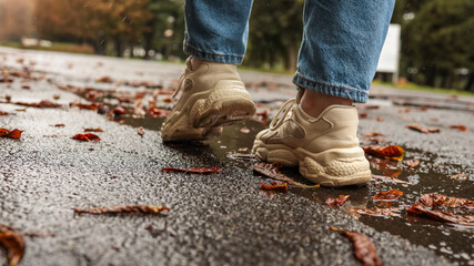 Walking through autumn puddles in casual sneakers and jeans