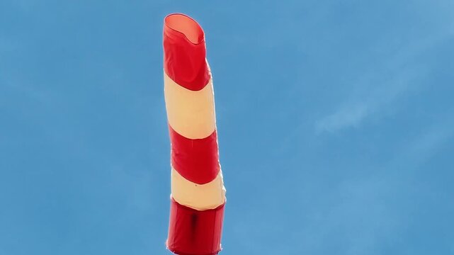  Red and white windsock blowing in the wind at an airfield