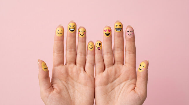 Human hands with colorful smiley face icons on fingers over pink background