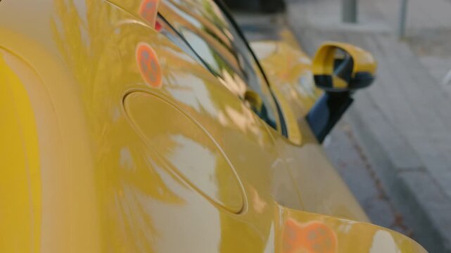 Extreme close-up of a yellow sports car's curved fender with an abstract palm tree reflection, Cote d'Azur, France