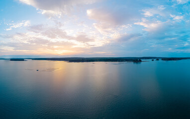 Obraz premium Freeport, Maine coastal aerial view showing lush forested shorelines, small islands, and tidal flats reflecting soft pastel sunset light over Casco Bay.