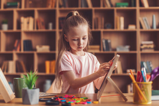 Focused Young Girl Playing With Colorful Alphabet Letters At Home, Engaged In Creative Learning Activity At Desk Surrounded By Learning Materials And Tools. Education And Development Concept.