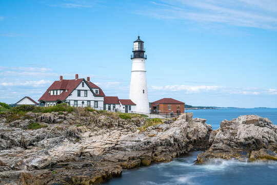 Portland Head Light standing atop rugged rocky cliffs along Casco Bay in Cape Elizabeth, Maine, Long Exposure photo.