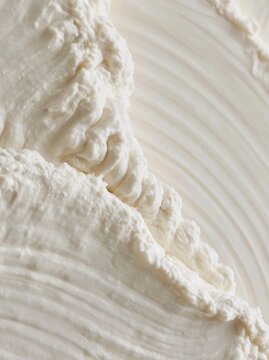 Close-up of a creamy white substance, which appears to be whipped cream. the texture of the substance is smooth and fluffy, with a wavy pattern that creates a wave-like effect.