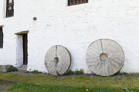 Visitors see old millstones near a white building in Beasain, Gipuzkoa, Basque Country, Spain during day