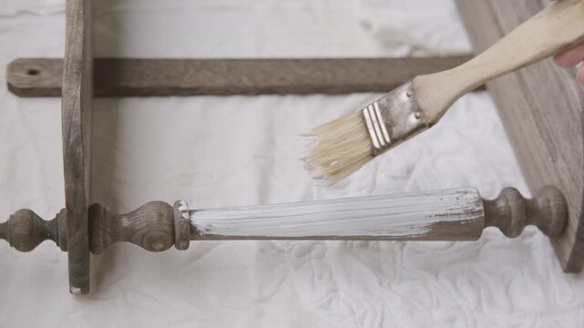 brush applying paint to old wooden furniture during furniture restoration, vintage bookcase restoration process, DIY home improvement and shabby chic style renovation project, hobby tool