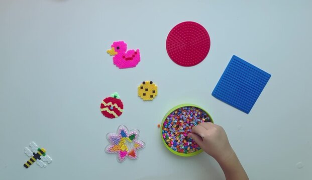 ​Top View of Child's Hands Sorting Colorful Fuse Beads