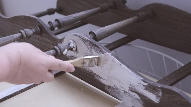 brush applying paint to old wooden furniture during furniture restoration, vintage bookcase restoration process, DIY home improvement and shabby chic style renovation project, hobby tool