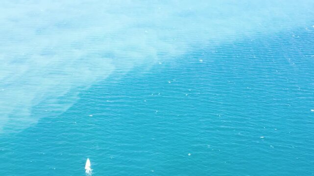 Aerial view of a crystal clear sea water texture. View from above Natural blue background. Blue water reflection. Blue ocean wave. 