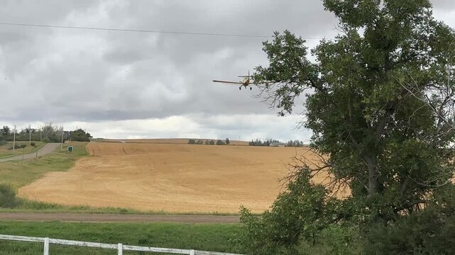Crop Duster Airplane Flying Across Agricultural Farmland While Spraying Crops in a Rural Farming Landscape