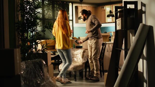 Playful couple doing a silly dance in their new house after moving day, as happy homeowners celebrate the achievement of buying their first home with fun, ecstatic moves and a fresh start indoors.