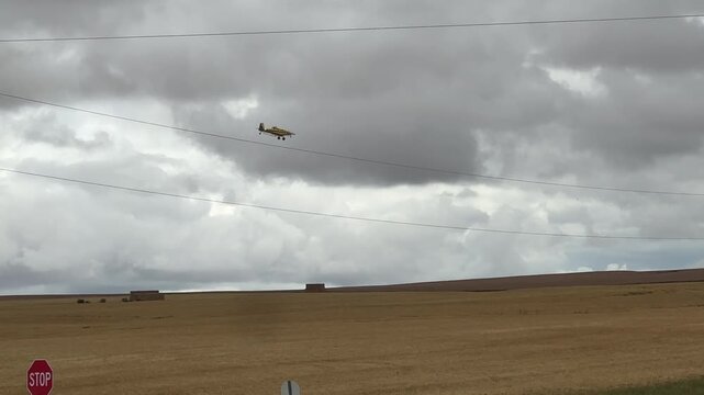 Crop Duster Airplane Flying Low Over Agricultural Farming Fields During Rural Alberta Farm Operations