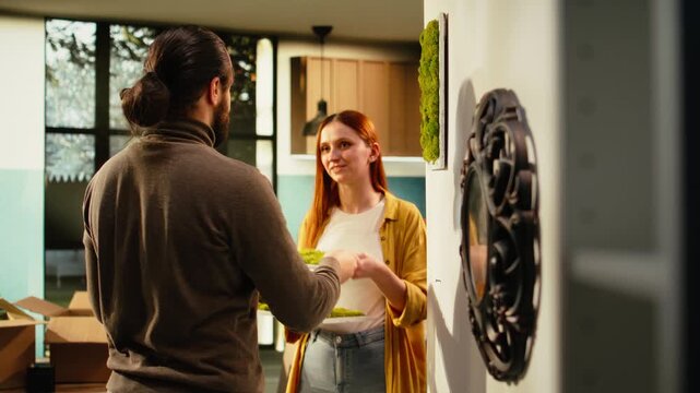 Close-up of a couple placing decorations on the wall in a new house, creating a cozy first home while enjoying redecoration and the satisfaction of settling in.