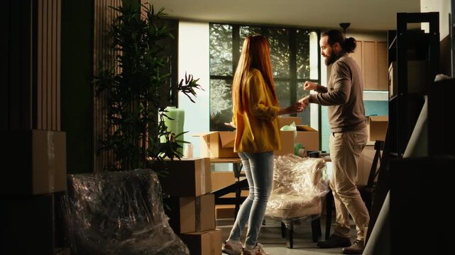 Playful couple performs a silly dance in their new house after moving day, capturing happy homeowners celebrating the achievement of buying a first home with ecstatic and authentic emotions indoors.