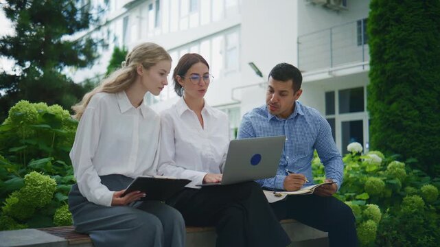 Group of business people working together outside in a garden area during daylight hours