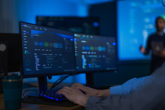 A close view of a blue monitoring dashboard on a widescreen monitor reveals coloured status badges shifting across a cloud control panel in a modern technology company