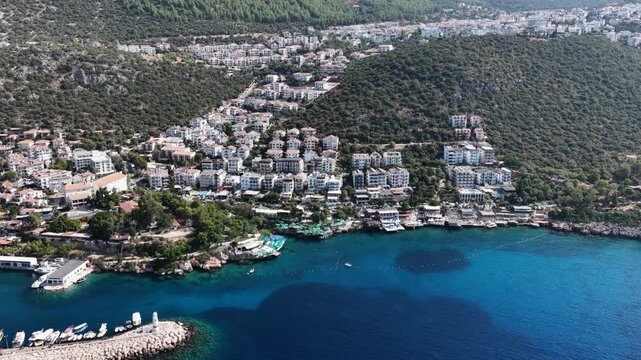 Aerial tracking shot moving right, revealing a beautiful coastal city built on green hills next to the deep blue Mediterranean Sea.