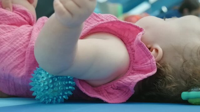 Close-up of a baby girl's face resting on a play mat with a pacifier