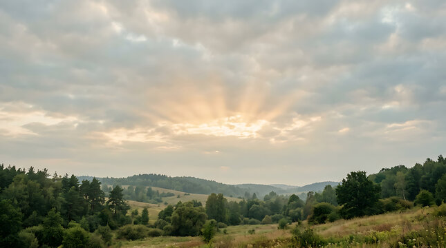 Soft crepuscular rays break through cloudy sky over green rolling hills in rural valley.