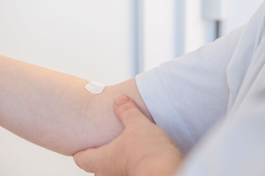 arm with patch on skin, indicating medical treatment, medical care, adhesive bandage, band-aid after blood donation, plaster after giving blood for medical tests and laboratory analysis