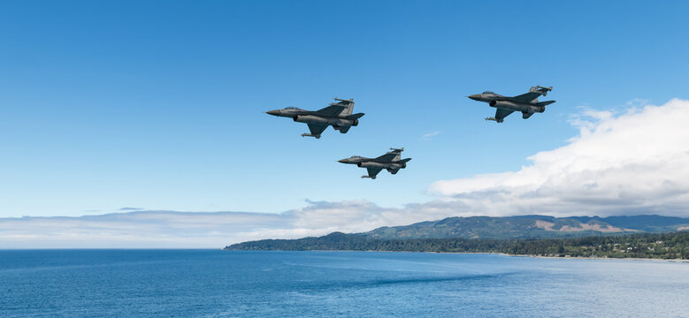 Three Fighter Jets Flying In Formation Over Ocean Coastline With Blue Sky Background From BC Canada