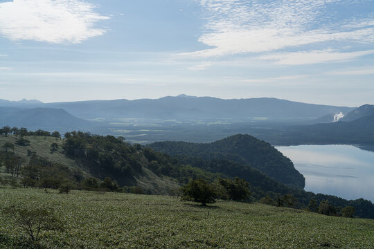 Wide caldera lake and rolling green hills in soft morning light
