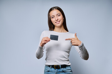 Smiling woman holding black plastic transport card on grey background