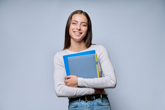 Young female student holding folders laughing looking at camera