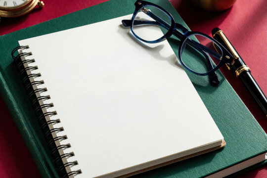 Spiral notebook with One Day Day One text on green book cover. Blue glasses, black fountain pen lie on desk. Concept of motivation, goal setting, planning for personal growth business success in