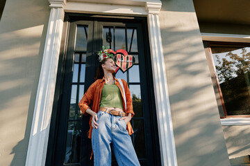 Young woman standing outdoors near a house door. Concept of lifestyle and fashion. Natural lighting...