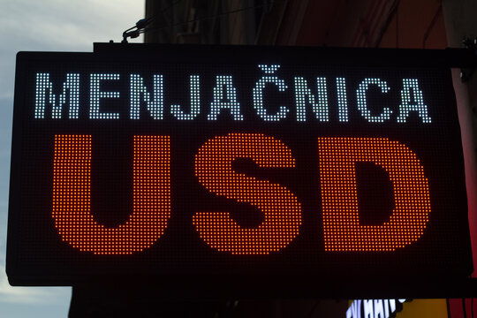 Street photo. Electronic LED exchange sign with text USD. Bright digital display showing currency exchange rates. Money transfer, economy, bill. Translation from Serbian: Currency exchange office