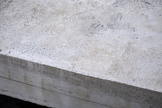 Layer of concrete slab. Concrete edge revealing rough textured top surface and smooth formed sides. Useful for construction, architecture, civil engineering, and industrial design backgrounds.